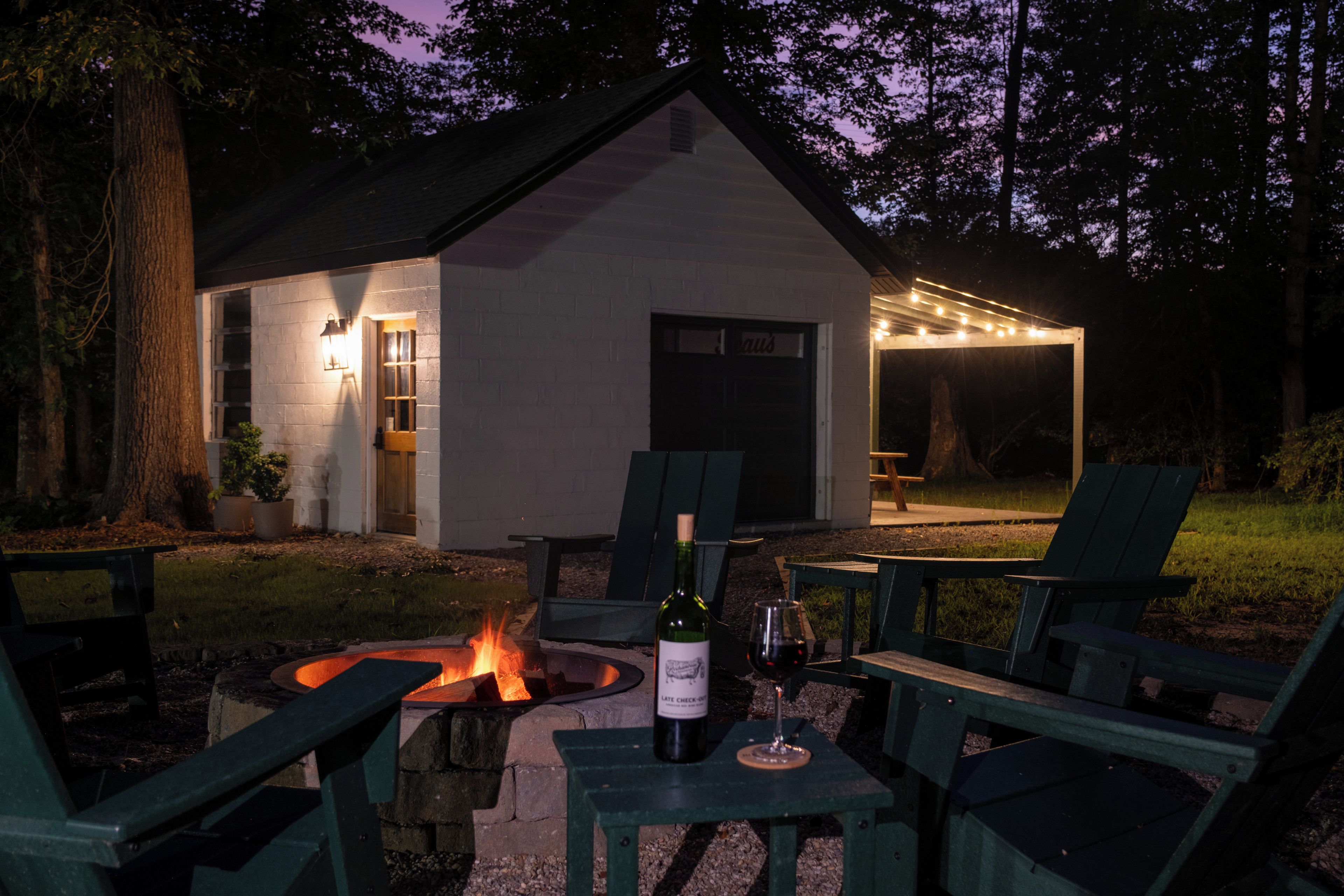 Un área de estar al aire libre acogedora, con un brasero, una mesa y una botella de vino, además de sillas.