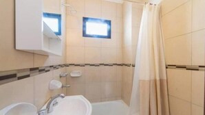 Un baño con lavamanos, espejo, ducha y paredes con azulejos.