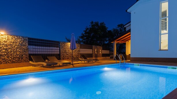 A swimming pool with lounge chairs and a stone wall.