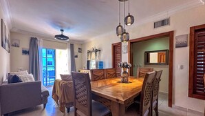 A dining area with a wooden table and chairs, a sofa, and a TV in the background.