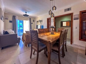 Un comedor con una mesa y sillas de madera, un sofá y un televisor al fondo.