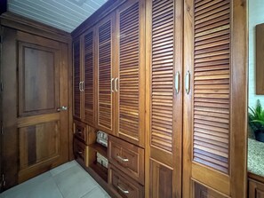 Una habitación con armarios de madera, un gran ventanal y una planta pequeña.