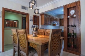 Un coin repas avec une table et des chaises en bois, un vase rempli de fleurs et un buffet en bois avec des étagères.
