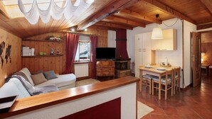 Un intérieur en bois comprenant un canapé, un téléviseur, une cheminée et un coin repas.