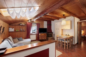 A wooden interior with a sofa, TV, fireplace, and dining area.