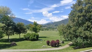 Un parc avec des arbres, un sentier et une chaîne de montagnes qui se dessine à l’horizon.