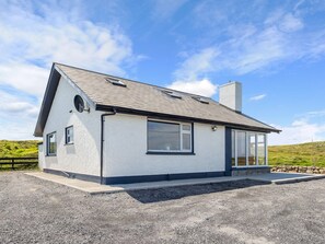 A modern single-story house with a sloped roof, large windows, and a stone foundation.
