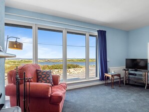 A room with a large window, a red sofa, a television, and a small table.
