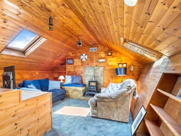 A cozy cabin interior with a stone fireplace, wooden walls, a sofa, and a small table.