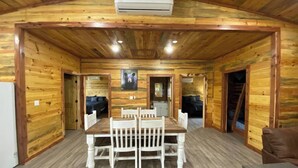 A wooden cabin with a dining area, two bedrooms, and a bathroom. - The Bear Den ATV friendly (Mena)