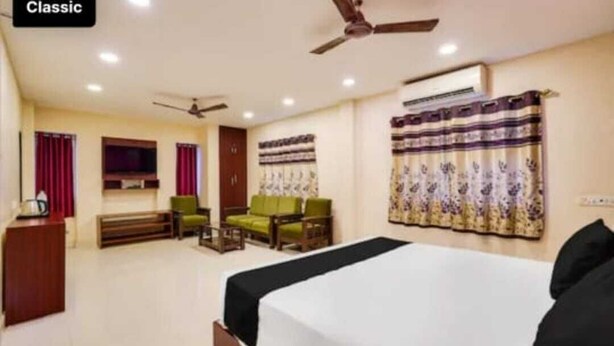 A hotel room with a bed, a desk, a chair, a sofa, and a ceiling fan. - Five stones By Terra Hotel T Nagar (Chennai)