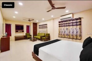 A hotel room with a bed, a desk, a chair, a sofa, and a ceiling fan. - Five stones By Terra Hotel T Nagar (Chennai)