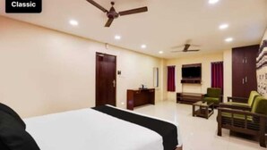 A hotel room with a bed, a desk, a chair, a sofa, and two ceiling fans. - Five stones By Terra Hotel T Nagar (Chennai)