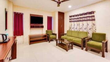 Una sala de estar con un sofá, dos sillones, una mesa de centro y un televisor.
