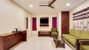 A living room with a sofa, a coffee table, a TV, and a ceiling fan. - Five stones By Terra Hotel T Nagar (Chennai)