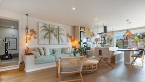 Una sala moderna con un sofá, sillas de mimbre y una zona de comedor con mesa.
