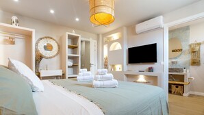 Un dormitorio moderno con una cama grande, televisor y un baño con espejo y toalleros.
