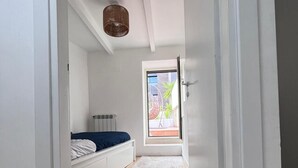 A bedroom with a bed, a window, a radiator, and a wooden floor. - Testaccio Terrace (Roma)