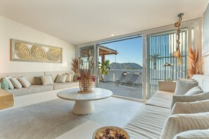 A modern living room with a sofa, a round coffee table, and a large window with a view of mountains. - Villa Oceania Entire with Sea View, Wi-Fi and Air Conditioning (Chayofa)