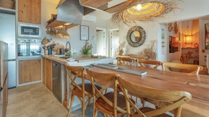 A modern kitchen with wooden cabinets, a built-in oven, and a dining area with a large wooden table and chairs. - Villa Oceania Entire with Sea View, Wi-Fi and Air Conditioning (Chayofa)