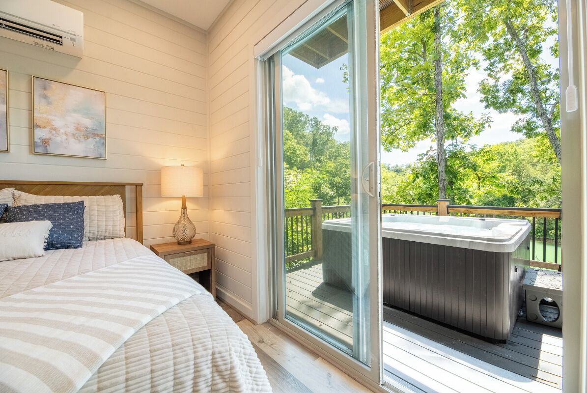 Ein Schlafzimmer mit einem großen Bett, einem Nachttisch, einem Fenster und einer Außenwhirlpool-Badewanne auf einer Terrasse.