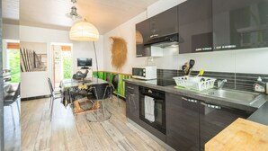 A modern kitchen with a dining area, wooden flooring, and a ceiling fan. - Holiday Home 'Du Porche' with Private Terrace and Wi-Fi (Chaillevette)