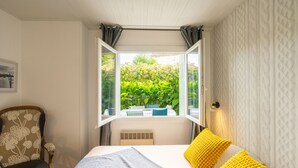 A bedroom with a bed, a chair, a window, and a view of greenery. - Holiday Home 'Du Porche' with Private Terrace and Wi-Fi (Chaillevette)