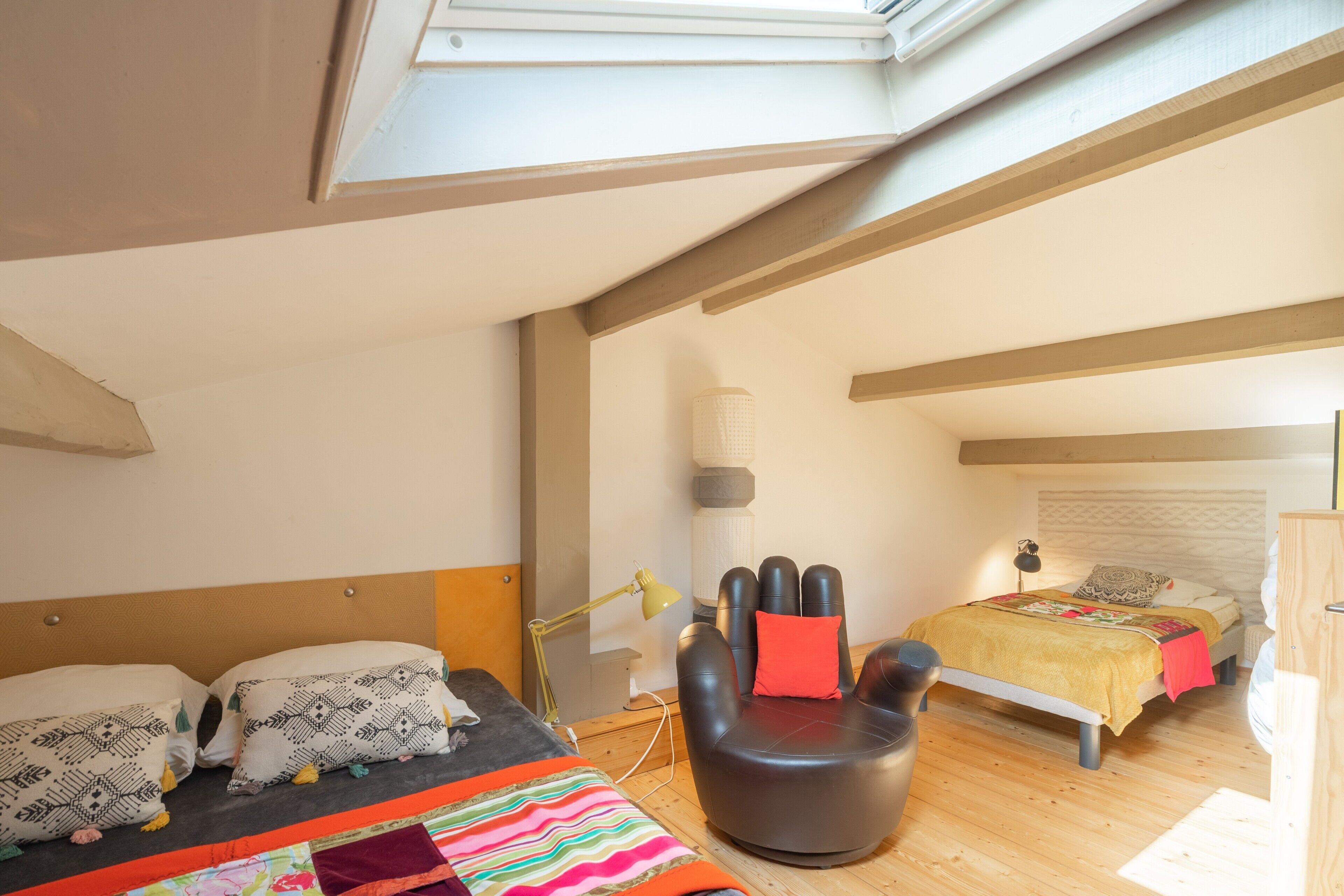 A bedroom with a skylight, two beds, a sofa, and a lamp.