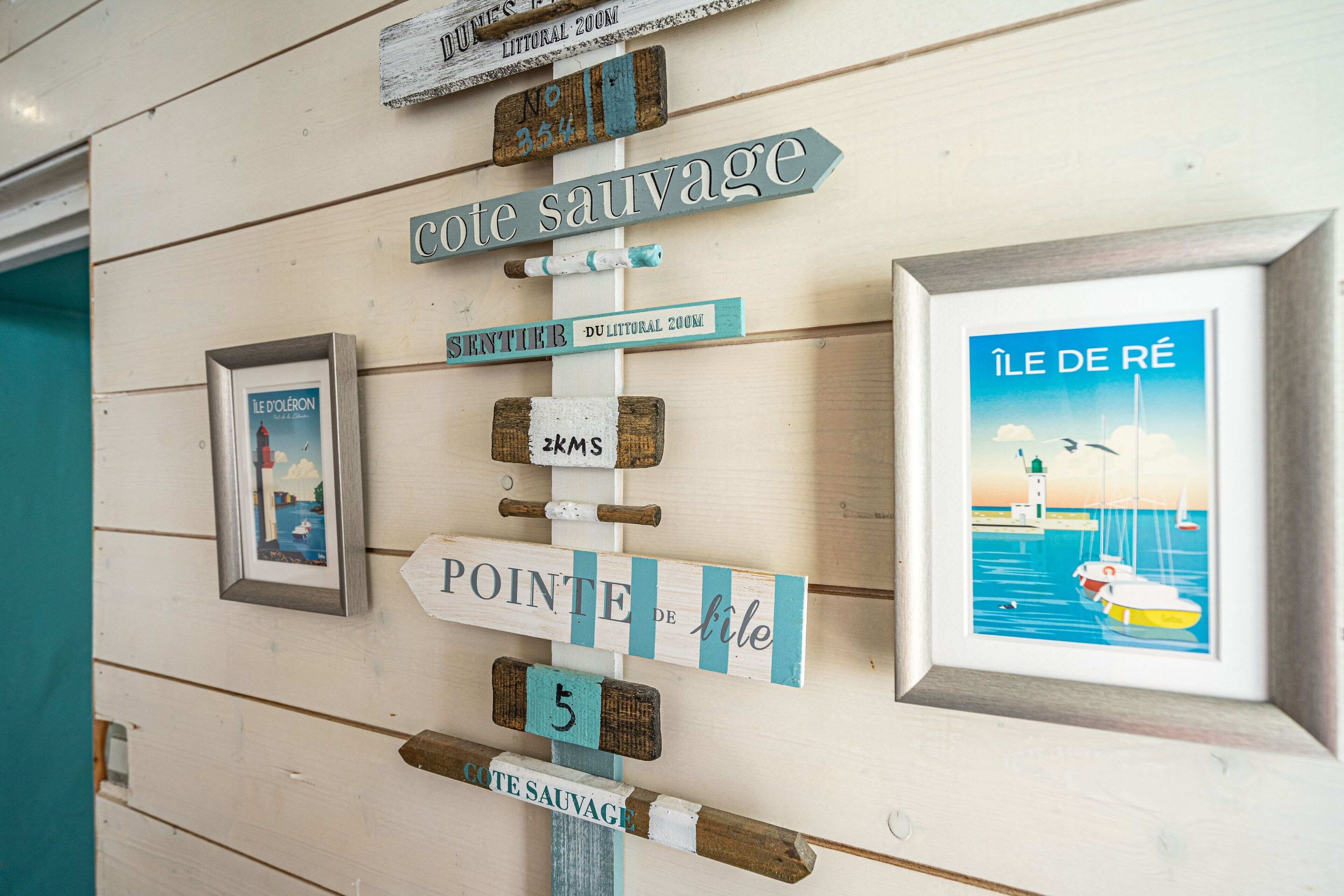 A wall with directional signs and a framed picture of a lighthouse.