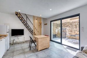 A modern kitchen with a TV, wooden staircase, and a dining area with a table and chairs.