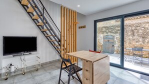 A modern interior with a wooden staircase, a flat-screen TV, a dining table, and a view of the outside. - Apartment 'Le Poulailler D'alice' with Private Terrace, Wi-Fi and Air Conditioning (Saint-Génies-de-Fontedit)