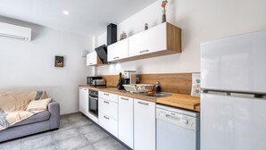 A modern kitchen with white cabinets, a wooden countertop, a built-in oven, and a dishwasher. - Apartment 'Le Poulailler D'alice' with Private Terrace, Wi-Fi and Air Conditioning (Saint-Génies-de-Fontedit)