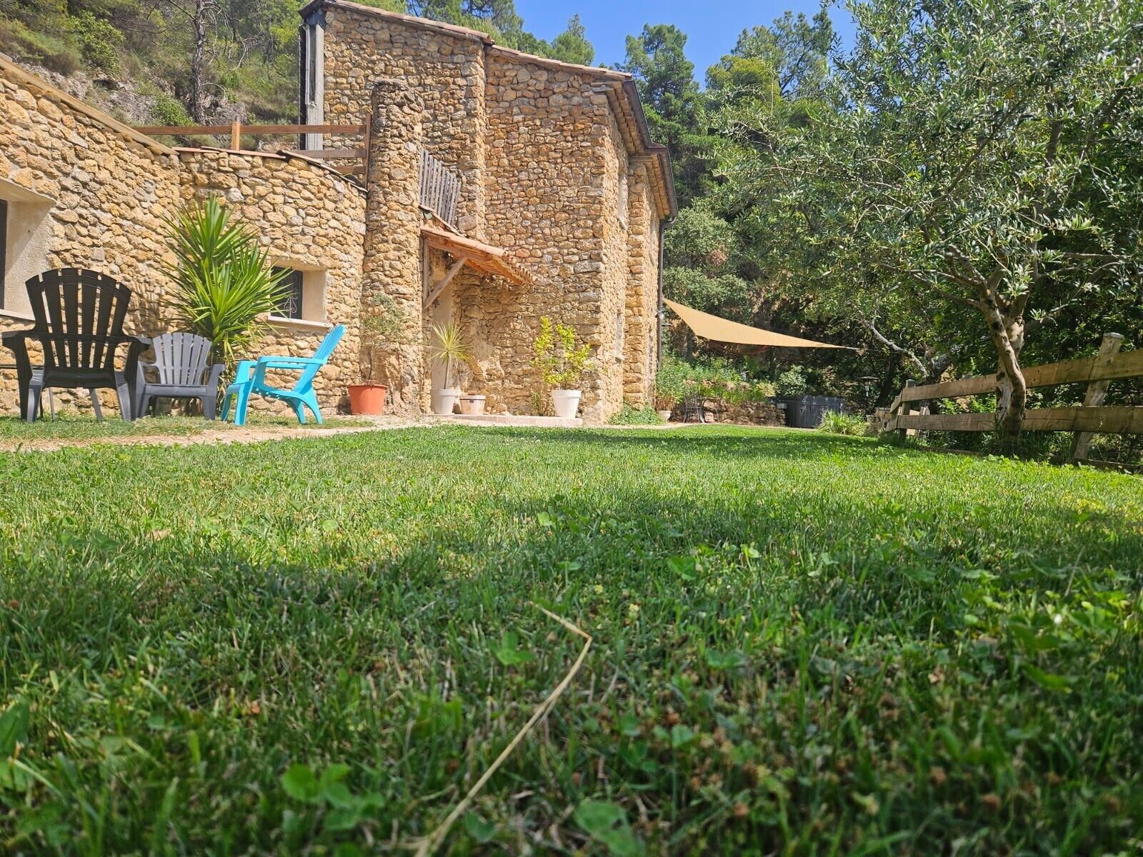A stone building with a grassy yard, outdoor seating, and a wooden fence.