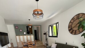 A modern living room with a sofa, coffee table, and a dining area with chairs and a table.