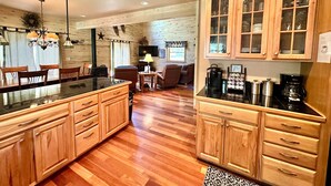 A kitchen with wooden cabinets, a dining area with chairs, a television, and a fireplace. - Explore more. Relax More. Escape to the mountains! (Cimarron)