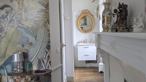 Ein Flur mit Wandverkleidung, einem Spiegel, einer weißen Kommode und einem Kamin.