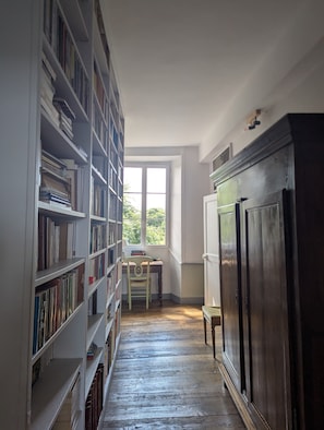 Une bibliothèque avec des étagères, un bureau et une fenêtre.