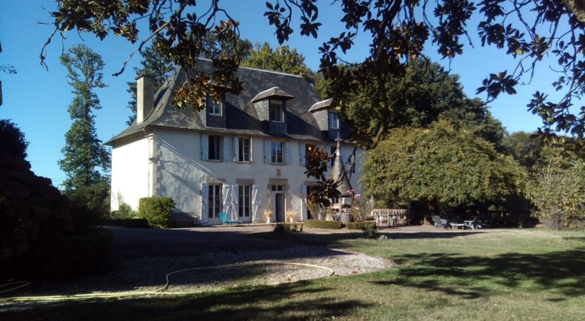 A two-story house with a large front lawn and a tree in the foreground.