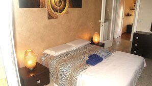 A bedroom with a bed, two bedside tables, a lamp, and a mirror.