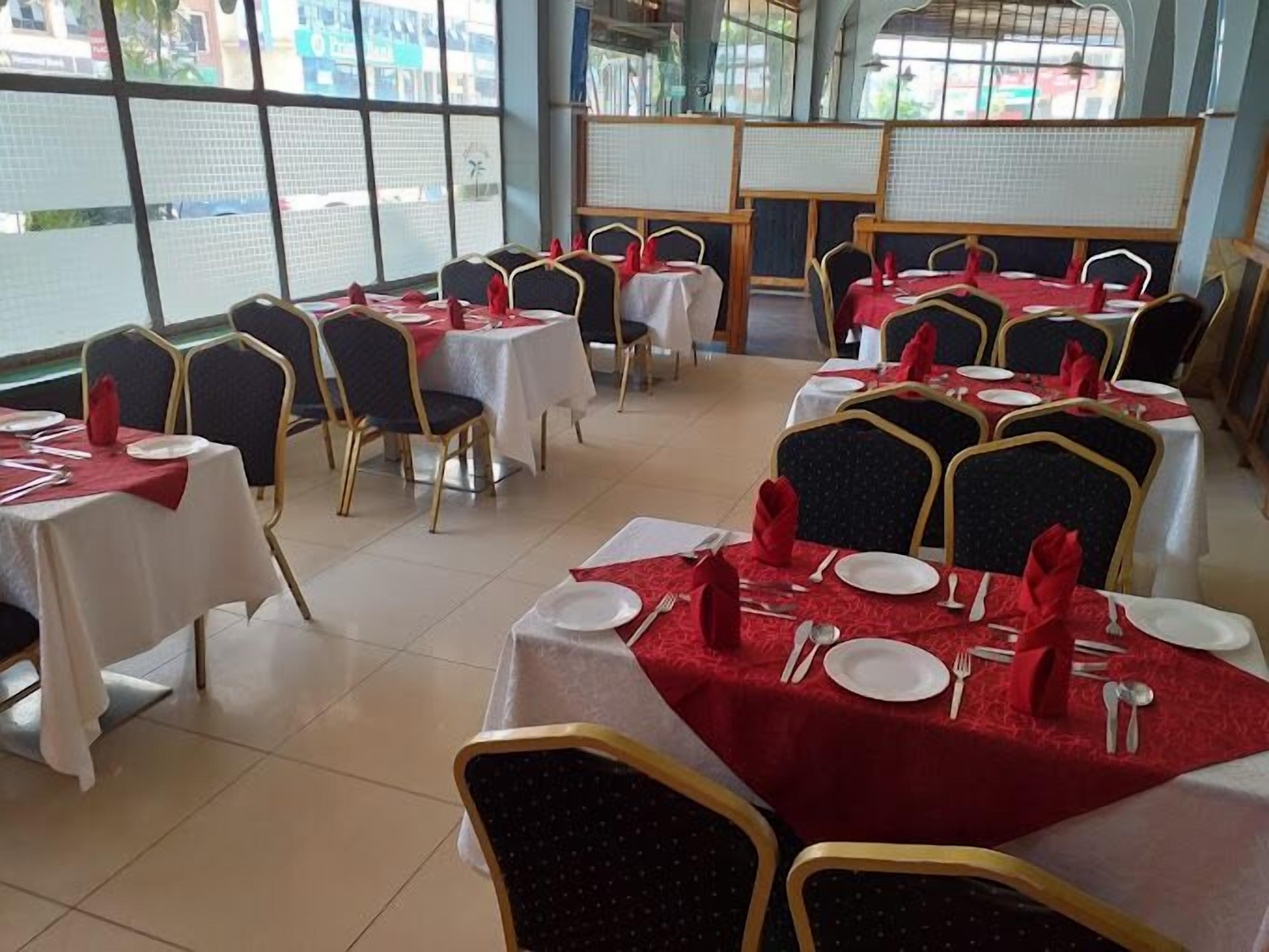 A restaurant with tables set for dining, featuring a view through large windows.