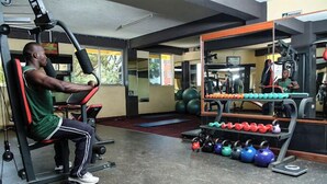 Un gimnasio con equipo de ejercicio, que incluye una prensa de banca, pesas de cañón y un soporte para pesas.