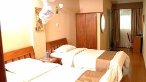 Habitación de hotel con dos camas, un armario de madera, un escritorio con silla y una ventana con cortinas.