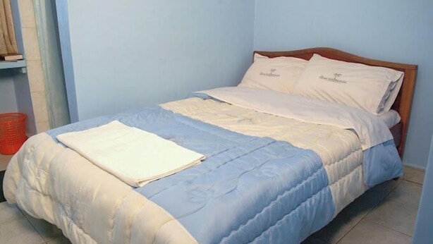 Una cama individual con edredón azul y blanco, dos almohadas y una sábana blanca doblada sobre la cama.