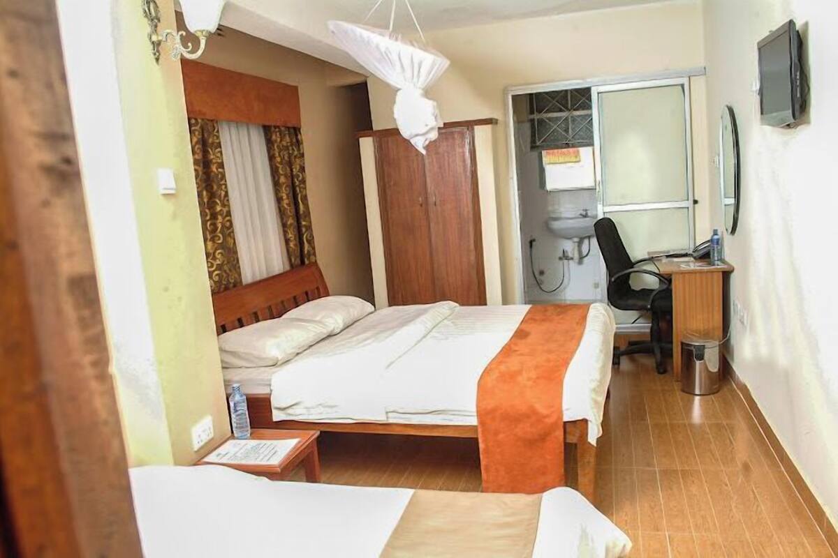 A hotel room with a bed, a desk, a chair, a wardrobe, and a television.