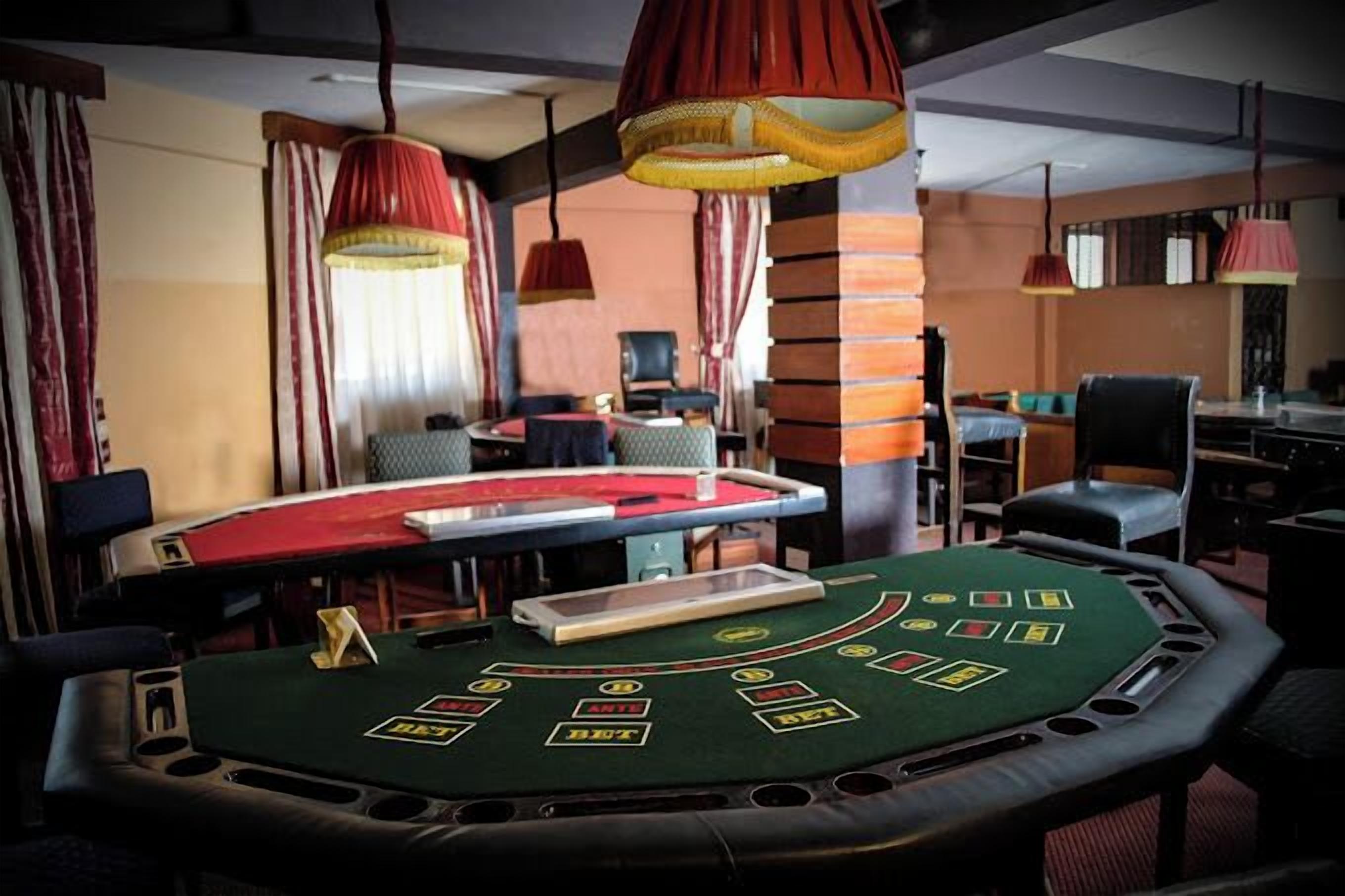 A casino table with a green felt surface, red and yellow hanging lamps, and a brick pillar.