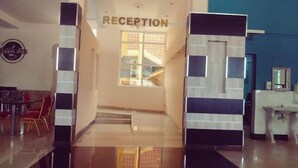 Zona de recepción con un cartel que dice "RECEPTION" y una escalera que sube a un piso superior.