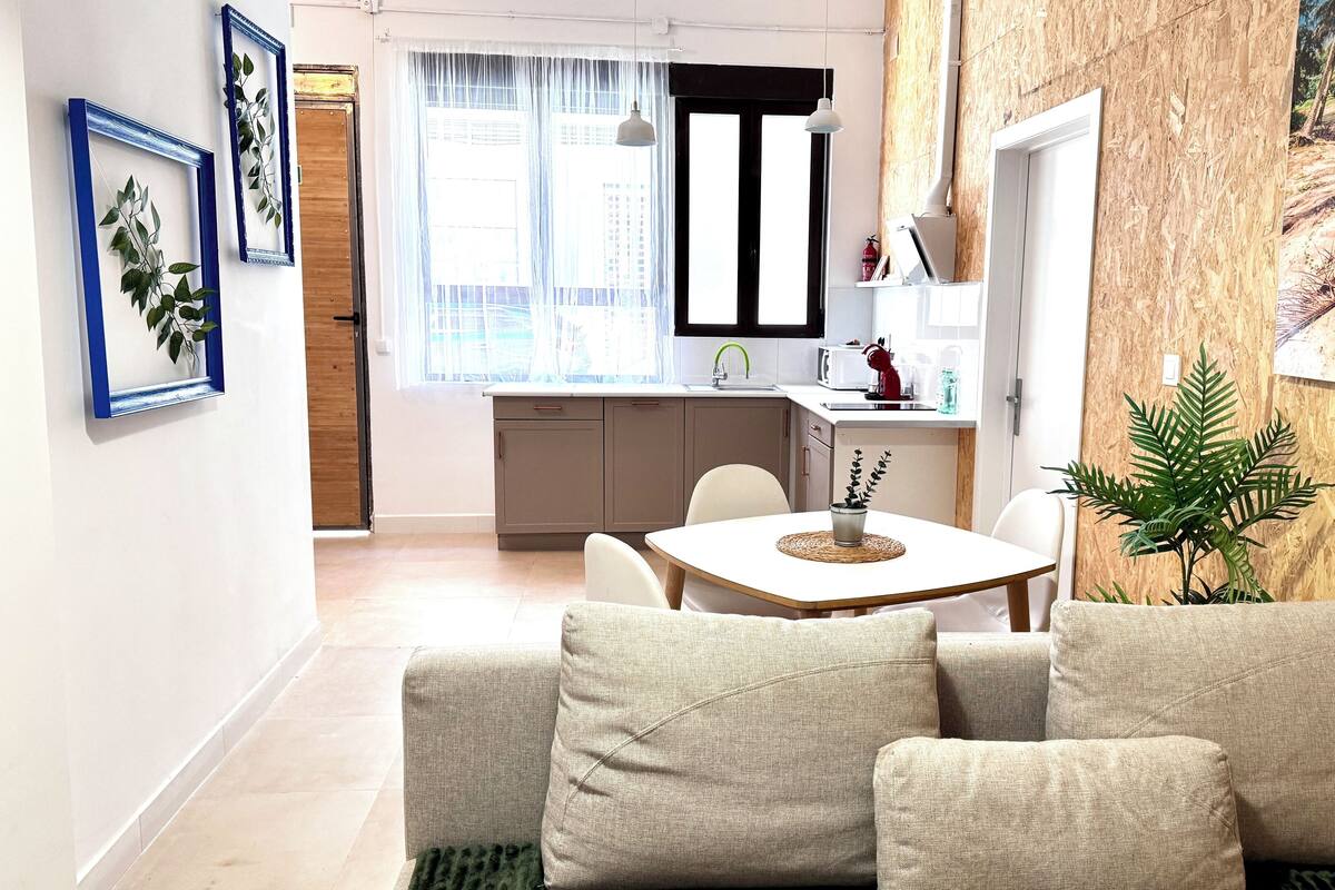 A modern kitchen with a sink, cabinets, and a window with sheer curtains.