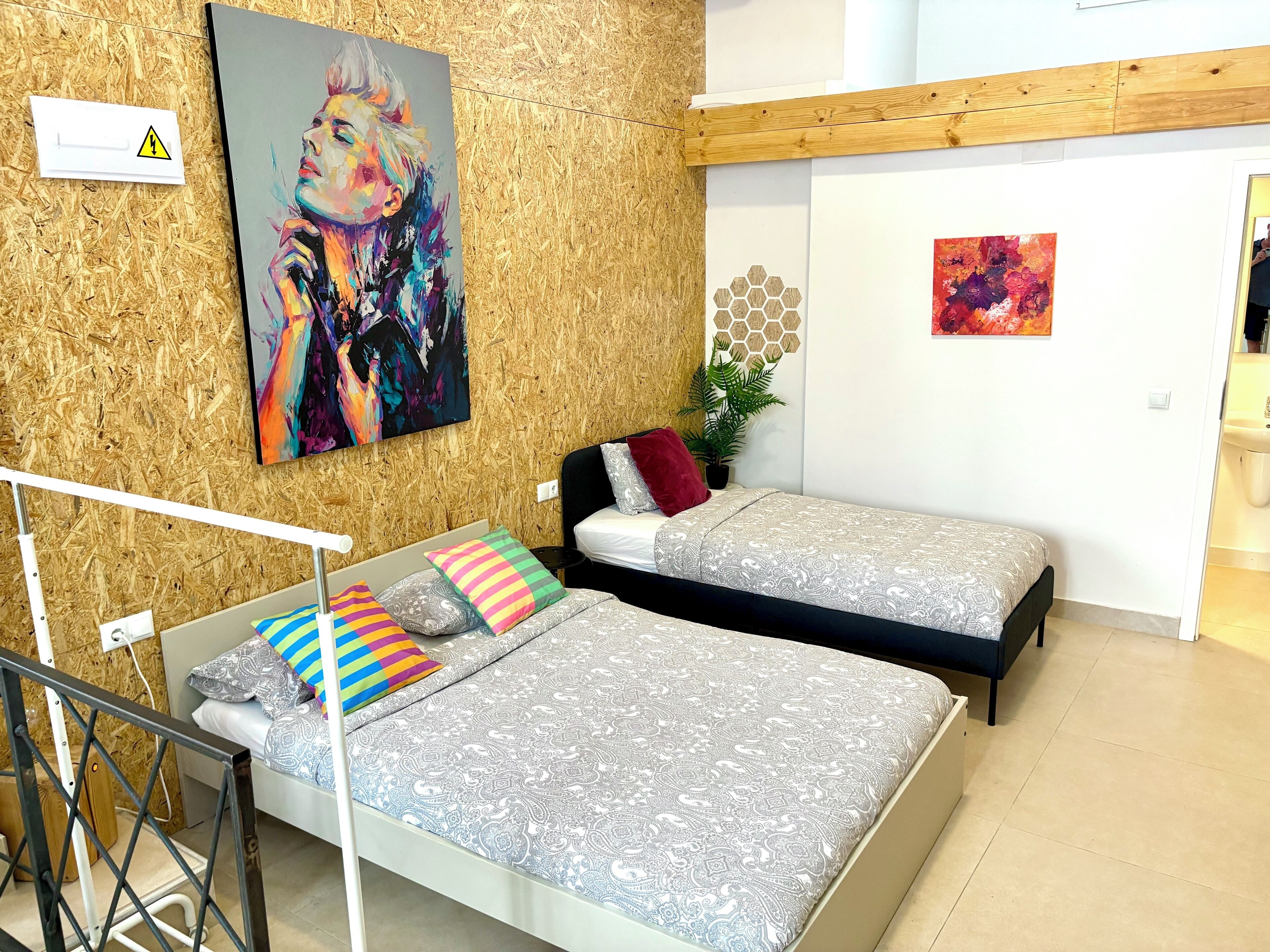 Un dormitorio con dos camas, una pared de madera y un cuadro.