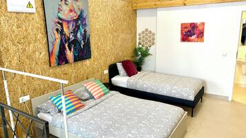 Un dormitorio con dos camas, una pared de madera y un cuadro.