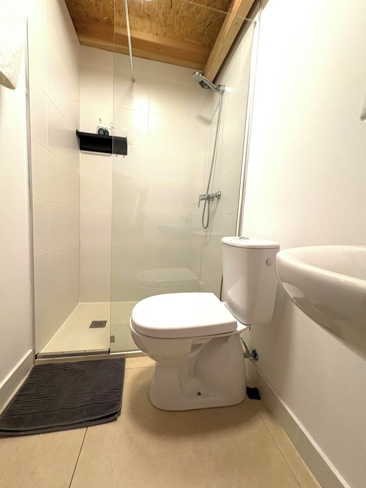 A bathroom with a toilet, a shower enclosure, and a sink.